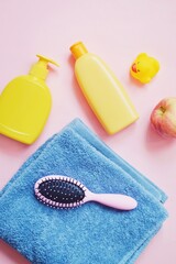 Flat lay beauty photo yellow liquid soap package, shampoo bottle, rubber duck, blue towel and hair brush