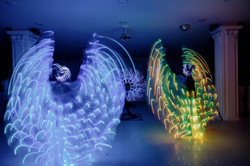 People in luminous costumes dance in the dark for a holiday