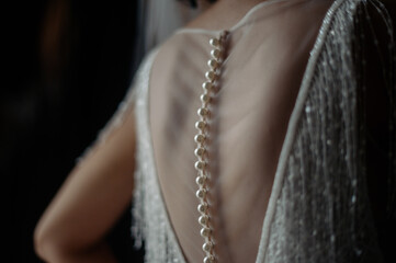 A white wedding dress is knitted to the bride. A bride is being helped to wear the wedding dress....