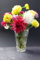 fresh colorful asters bouquet in cristal vase on black background