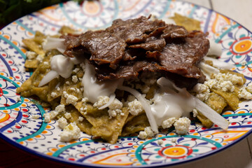 Mexican green chilaquiles with cecina beef steak on white background