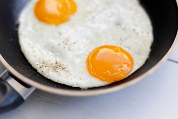 Fried eggs in pan on white table. Close up