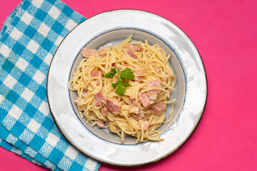 creamy spaghetti pasta with ham on pink background