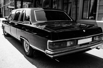 Obraz na płótnie Canvas Black luxury retro car.Soviet retro car close up.retro car in black color at the minimalistic background of desert terrain and blue sky.