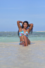Fototapeta premium Sensual Hispanic young woman siting inside water waist up stroke her long black hair