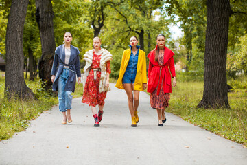 Four fashion models walking in autumn park