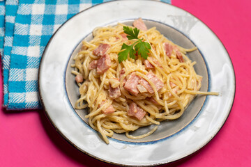 creamy spaghetti pasta with ham on pink background