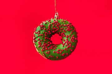 festive green donut on a red background in the form of a New Year toy. celebration, food art, holiday concept.
