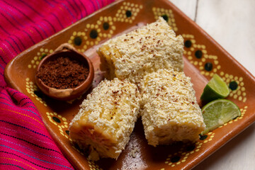 Mexican corn on the cob also called elotes with cheese and mayonnaise on white background