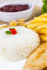 Rice with chicken filet and french fries on a white plate with a raw cotton dish towel. Selective focus