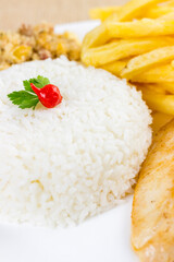 Rice with chicken filet and french fries on a white plate with a raw cotton dish towel. Selective focus