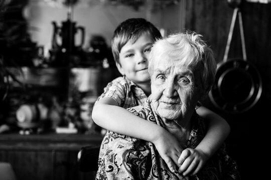 An old woman with her little grandson, closeup portrait. Black and white photography.