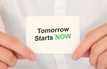 Man's hands take a card with words Tomorrow starts NOW, finance and business concept.