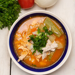 Mexican chicken soup with vegetables and rice on white background