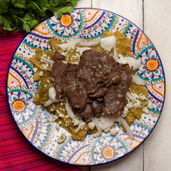Mexican green chilaquiles with cecina beef steak on white background