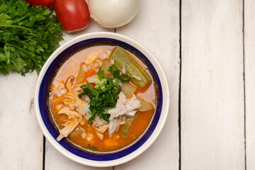 Mexican chicken soup with vegetables and rice on white background