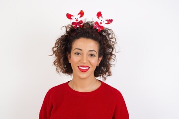 Young arab woman with curly hair wearing christmas headband standing on white background with a happy and cool smile on face. Lucky person.