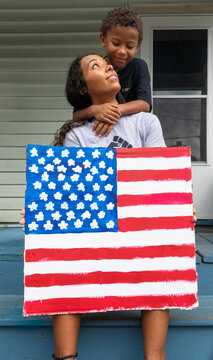 Multi Ethnic Mother and Son Holding Hand-Painted American Flag Protest Sign
