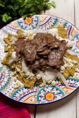 Mexican green chilaquiles with cecina beef steak on white background