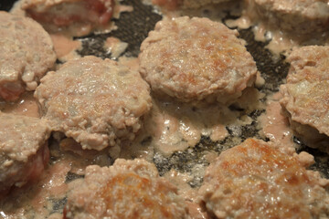 Meat cutlets are fried in frying pan.