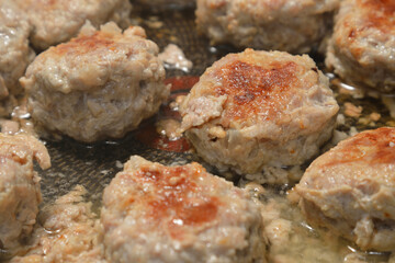 Meat cutlets are fried in frying pan.