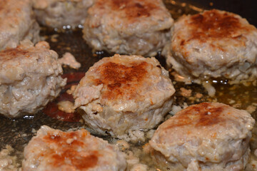 Meat cutlets are fried in frying pan.