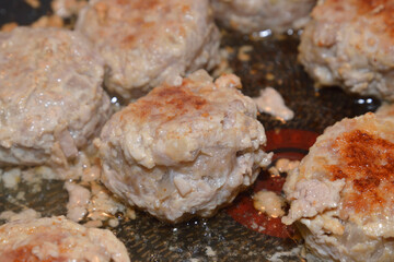 Meat cutlets are fried in frying pan.