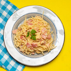 creamy spaghetti pasta with ham on yellow background