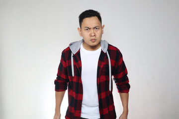 Fototapeta premium Portrait of funny Asian man showing cynical unhappy angry facial expression, looking at camera over white