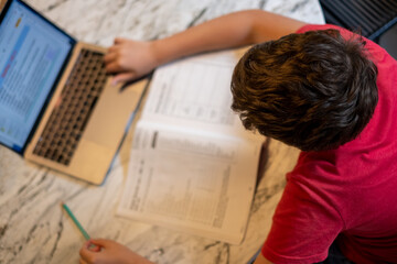 A young kid is doing homework at home during the pandemic quarantine 
