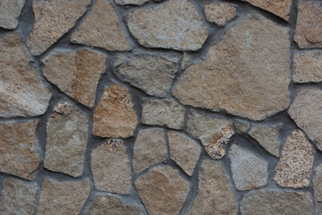 decorative texture of the building foundation made of light colored stones of any shape and different sizes; covering of building's foundation