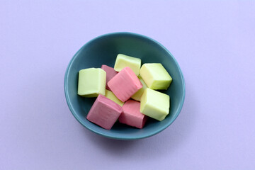 Fruit juice chew candies in small blue candy bowl on lavender background