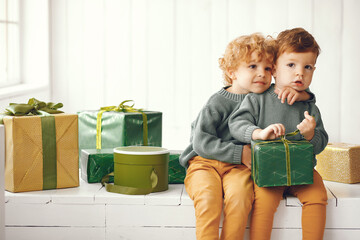 Cute little boys in a studio. Children sitting by the christmas gifts. Kid in a gray sweater.