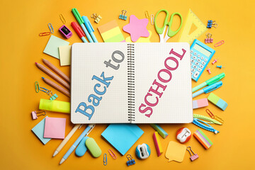 Notebook with text Back To School surrounded by different stationery on yellow, flat lay