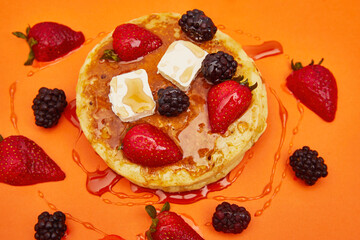 Delicious pancakes with butter, strawberries, blackberry and honey