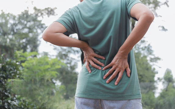 Closeup hands of woman touching her back pain in healthy concept on nature background.