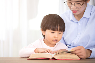 Fototapeta na wymiar Mother tutoring daughter reading at home