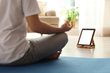 Man practicing yoga while watching online class at home during coronavirus pandemic, closeup. Social distancing