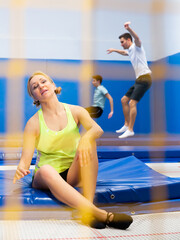 Naklejka premium View through yellow safety net of tired sporty woman having break during trampoline training