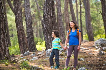 A woman walks with her son through the forest.
