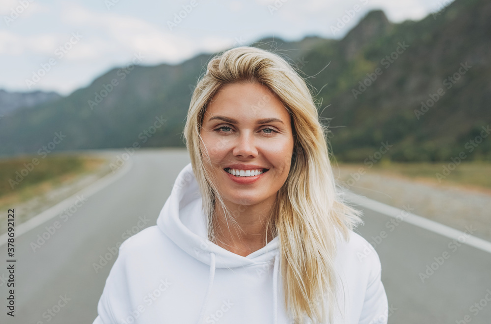 Canvas Prints Beautiful smiling blonde young woman traveler in white hoodie on road, trip to the mountains, Altai - Canvas Prints