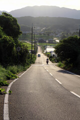 Fototapeta premium People driving motorcycle in countryside with mountains as background in Asuka