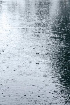 wet asphalt with raindrops in a puddle and some reflections