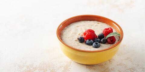 Healthy breakfast - oatmeal with berries and nuts in a bowl on the table.