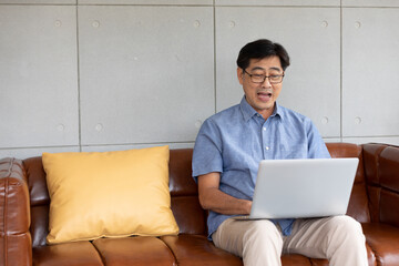 asian senior man using computer laptop at home