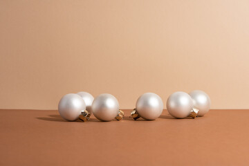 The girl's hand with white christmas balls is near the paper gift boxes with rope. Holiday concept. Idea for decoration presents. Beige background.