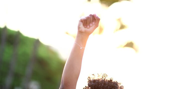 African American woman raises fist in air in political movement, black person activist