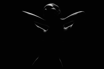 Nude Woman silhouette under light in the dark studio