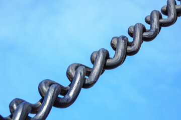     Large and heavy iron anchor chain against a blue sky.
