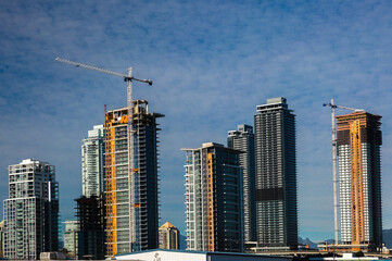 Fototapeta na wymiar Construction site in Burnaby City, construction of a new high-rise buildings in residential area of near the Sky Train station on the background of cloudy sky